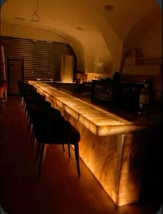 a dimly lit bar with stools at the end and lights on in the background