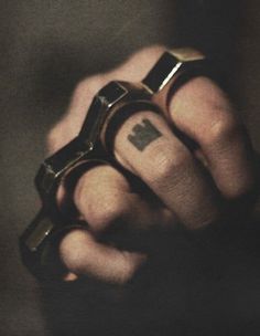 a person with a ring on their finger holding something in one hand and an arrow tattoo on the other