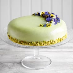 there is a cake with flowers on the top and frosting in the middle, sitting on a glass stand