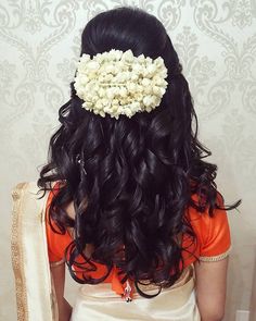 the back of a woman's head with long hair and flowers in her hair