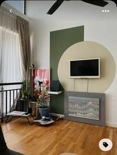 a living room with wood floors and a flat screen tv mounted on the wall above a fireplace