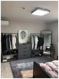 a bedroom with a bed, dressers and clothes hanging on the racks in it