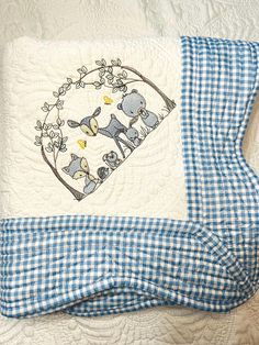 a blue and white quilted pillow with an elephant on it's side, sitting on top of a bed