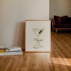 an art piece with a martini glass and olives on it next to a stack of books