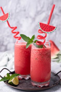 two glasses filled with watermelon drink on top of a plate