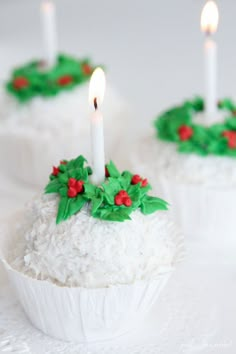 three cupcakes with frosting and holly decorations on them