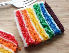 a slice of rainbow cake on a wooden table