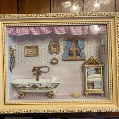 a miniature bathroom is displayed in a gold frame