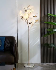 a living room with a couch and a lamp on the floor next to a plant