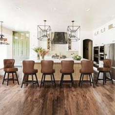 a large kitchen with wooden floors and white cabinetry, along with a center island