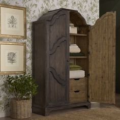 an armoire with two drawers and some towels in it next to a potted plant