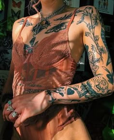 a woman with lots of tattoos on her arm and chest is posing for the camera