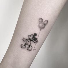 a person with a mickey mouse tattoo on their arm holding a balloon in the shape of a heart