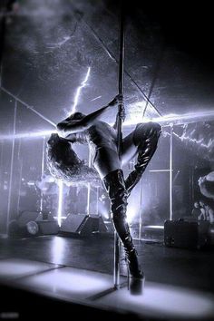 a woman in high heels is dancing on a pole with her legs bent over the pole