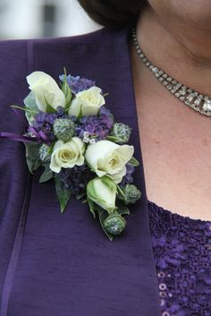 a woman wearing a purple dress holding a bouquet of white roses and broccoli