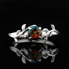 "Black Fire Opal Silver Leaf Branch Ring Lush and enchanting, this magnificent sterling silver leaf branch ring captures the awe and splendor of nature. The ring features a delicate branch of sterling silver leaves that wraps around the ring, giving the impression of a natural growth. The centerpiece of the ring is a stunning lab grown black fire opal gemstone. The black fire opal gemstone is known for its intense and mesmerizing dark hues and fiery flashes of color that resemble a blazing fire. Why buy from us? We do our best to make the ring buying process simple and easy for you. With this ring we include: ** Care put into each and every ring ** ** Easy Size Exchange ** ** FREE 1 Year Limited Warranty (See FAQ) ** ** A portion of the sale goes to support charity ** Buy with confidence k Black Fire Opal Rings, Opal Leaf Ring, Dragons Breath Fire Opal Engagement Ring, Black Fire Opal Ring, Black Fire Opal Engagement Ring, Dragons Breath Fire Opal, Fire Opal Engagement Ring, Black Fire Opal, Opal Gifts