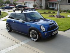 a blue car parked in front of a house with a ski rack on the roof