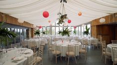 a banquet hall with tables and chairs covered in white draping, decorated with hanging paper lanterns