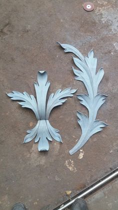 two metal florets sitting on top of a cement floor next to a pair of shoes