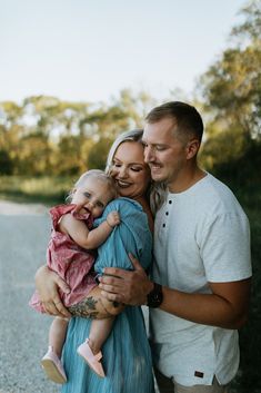 a man and woman holding a baby on the road