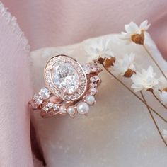 a close up of a ring on a pillow with flowers in the foreground and a pink fabric behind it