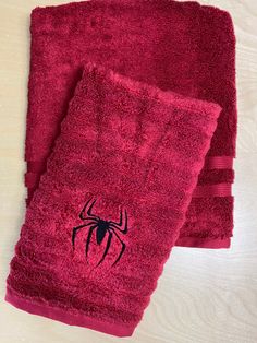 two red towels with black spider - man embroidered on the front and one is pink