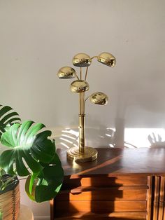 a gold lamp sitting on top of a wooden table next to a potted plant