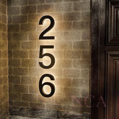 a brick wall with a lit up address sign on it's side and the number 205 written in black