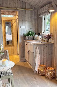 a kitchen with wooden walls and flooring next to a dining room table filled with flowers