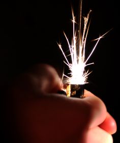 someone holding a lighter in their hand with some sparklers coming out of the top