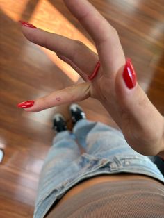 a woman's hand with red nail polish on it and her foot in the air