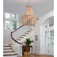 a chandelier hanging from the side of a stair case in a home with wood floors and white walls