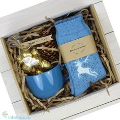 a blue mug and socks in a box with chocolates, pine cones and candy