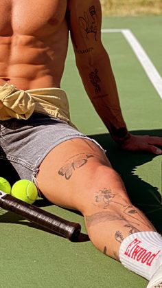 a shirtless man sitting on top of a tennis court holding a racquet