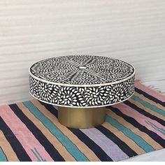 a black and white table sitting on top of a striped rug next to a wall