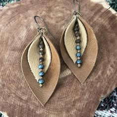 a pair of earrings with beaded details on top of a piece of wood sitting on a rug