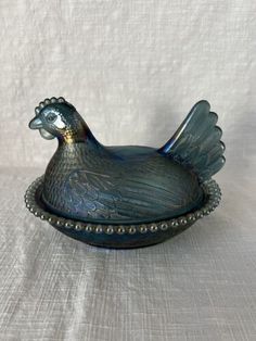 a decorative glass chicken dish on a white tablecloth