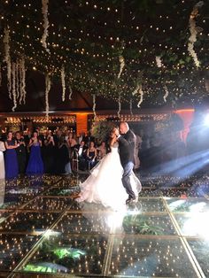 a bride and groom are dancing on the dance floor at their wedding reception in front of an audience