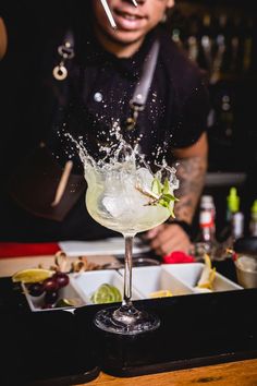 the bartender is making an alcoholic cocktail with ice and water splashing out of it