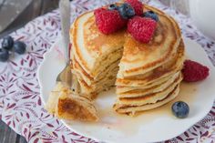 a stack of pancakes with berries on top and one slice cut out from the side