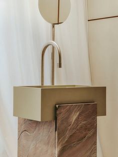 a marble sink with a metal faucet in the middle and a round light above it