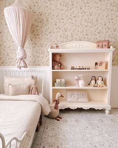 a white bed sitting next to a book shelf filled with books and stuffed animals on top of it