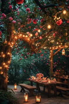 an outdoor dining area is lit up with lanterns and flowers on the trees, along with candles