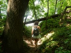 a woman with a backpack is walking through the woods