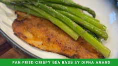 a white plate topped with fish and asparagus