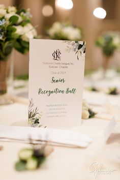 the table is set up with white flowers and greenery for an elegant wedding reception