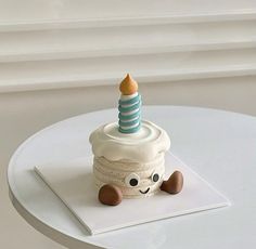 a small cupcake with a candle on top sitting on a white table next to a window