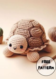 a crocheted turtle sitting next to two balls of yarn and a ball of knitting needles