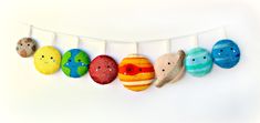 an assortment of stuffed animals hanging from a line on a white wall in the shape of eggs