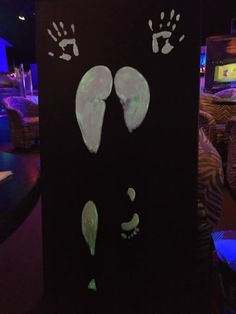 two hand and foot prints are projected on a black board in a room with blue lights